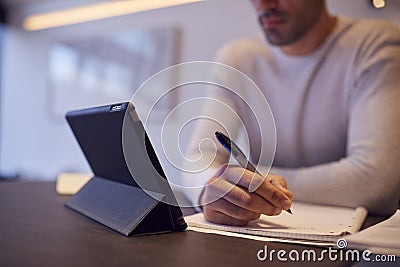 Close Up Of Man In Kitchen Working Or Studying From Home Using Digital Tablet Stock Photo