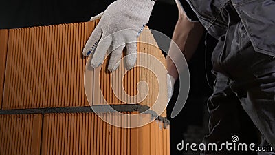 Close-up of man laying brick block on cement. Stock footage. Builder puts red brick blocks on top of each other holding Stock Photo