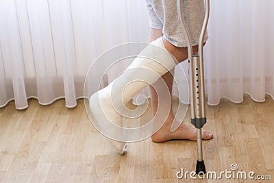 Close-up of man leg in plaster cast using crutches while walking. Stock Photo