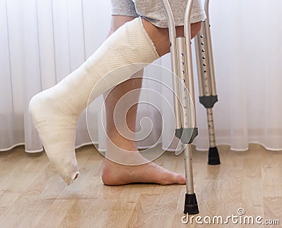 Close-up of man leg in plaster cast using crutches while walking. Stock Photo