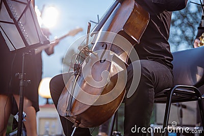 Male violoncellist playing cello in orchestra on the street Stock Photo