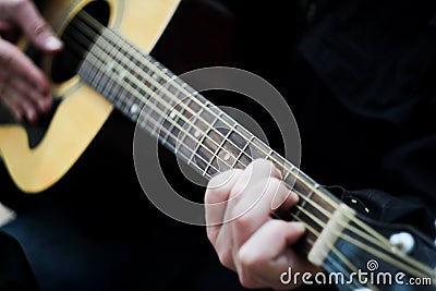 Close-up. A man playing a six-string acoustic guitar. Blurred Stock Photo