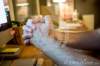 close-up of a man praying with the typical hands gesture in front of the screen of desktop computer in the evening in the home Stock Photo