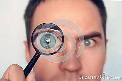 Close up of man`s face with the loupe close to one eye on white background. View to round human eye through the Stock Photo