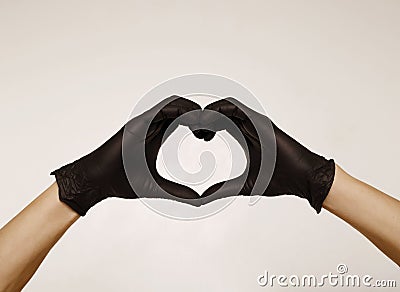 Close up man`s hands in black protective gloves making heart sign with hands over white background. Valentine`s Day, 8th March, Stock Photo