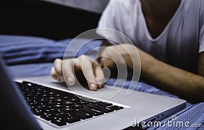 Close up of man`s hands using computer, surfing on internet and relaxing on bed Stock Photo