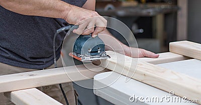 A man working on a home improvement project sanding wood with an electrical sander. Stock Photo