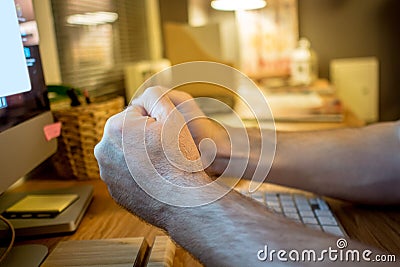 close-up of a man praying with the typical hands gesture in front of the screen of desktop computer in the evening in the home Stock Photo