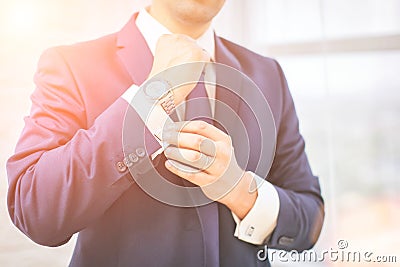 Close-up of man in suit with watch on his hand fixing his cufflink. groom bow tie cufflinks Stock Photo