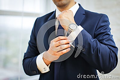 Close-up of man in suit with watch on his hand fixing his cufflink. groom bow tie cufflinks Stock Photo