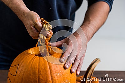 Male hands carving pumpkin taking out seeds Stock Photo