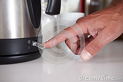 Close Up Of Man Turning On Switch To Boil Kettle Stock Photo