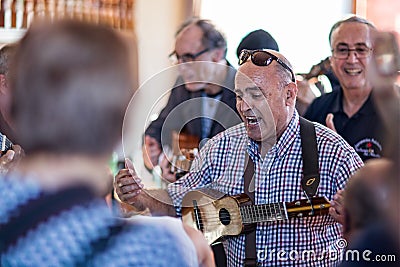 Close up of mature male musician passionately singing and playing ukelele inside a bar in Garachico, Tenerife, Spain Editorial Stock Photo
