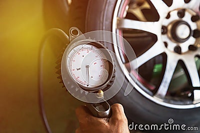 Close up mechanic inflating tire and checking air pressure Stock Photo