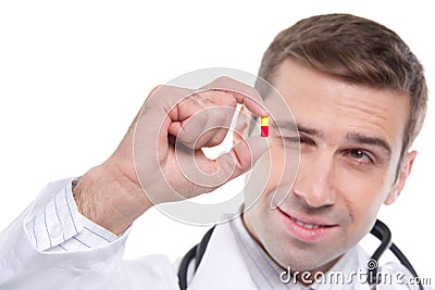 Close up of medical doctor holding small yellow-red pill Stock Photo