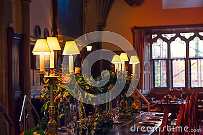 Close up medieval british castle interior dining table with plates, flowers and lamps. Warm light. Selective focus. copy space Editorial Stock Photo