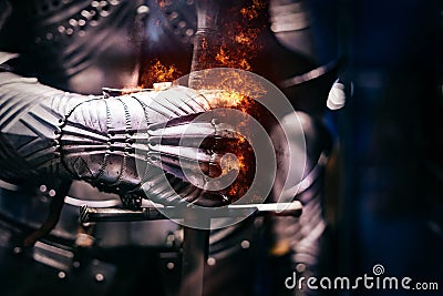 Close up of a Medieval steel armour with iron glove hand bursting with flames of fire Stock Photo