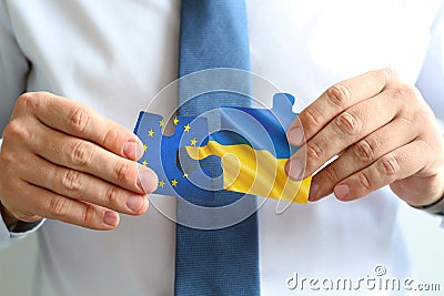 Close-up Of Men`s Hand Connecting Jigsaw Puzzle. Ukraine is joining European Union Stock Photo