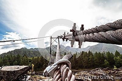 Close-up on a metal binding cable going in perspective to the bridge support with the texture of a summer sunny day. Reliability Stock Photo