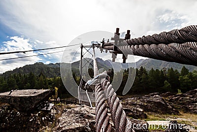 Close-up on a metal binding cable going in perspective to the bridge support with the texture of a summer sunny day. Reliability Stock Photo