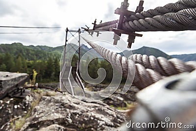 Close-up on a metal binding cable going in perspective to the bridge support with the texture of a summer sunny day. Reliability Stock Photo