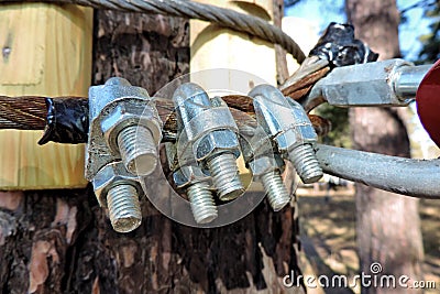 Close-up of metal ropes held together by clamps and bolts, steel wire rope and metal clamp are part of structure of rope park Stock Photo