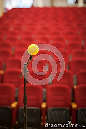 Close up of microphone in front of empty chairs hall. Before a conference, concert, seminar. Stock Photo