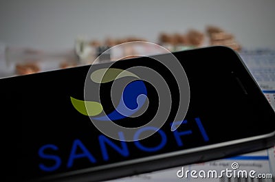 Close up of mobile phone screen with logo lettering of Sanofi pharmaceutical company, blurred pills and lab sheet background Editorial Stock Photo