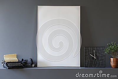 Close-up on mockup of poster between typewriter and clock in grey interior. Real photo Stock Photo