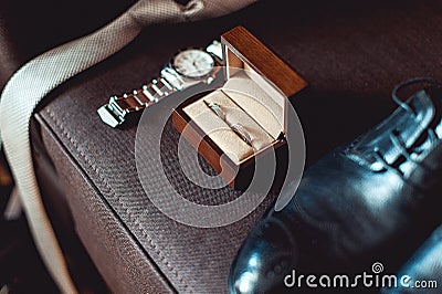 Close up of modern groom accessories. wedding rings in a brown wooden box, necktie, leather shoes and watch Stock Photo