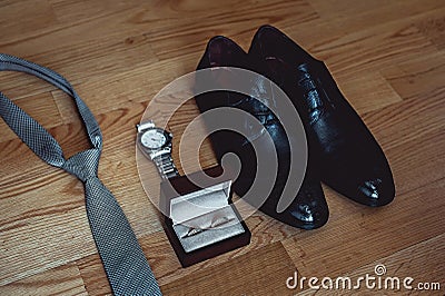 Close up of modern groom accessories. wedding rings, gray necktie, leather shoes and watch Stock Photo