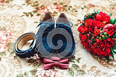 Close up of modern man accessories. Cherry bow tie, blue leather shoest and red wedding bouquet on a carpet. Stock Photo