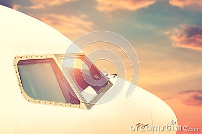 Close-up modern passenger commercial airplane cockpit flying against colorful dramatic sunset sky. Detail side view of Stock Photo