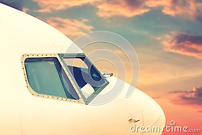 Close-up modern passenger commercial airplane cockpit flying against colorful dramatic sunset sky. Detail side view of Stock Photo