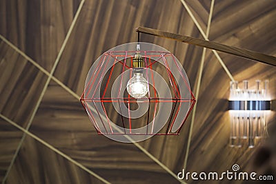 Close-up of a modern, red color copper lamp with bulb on wooden background Stock Photo