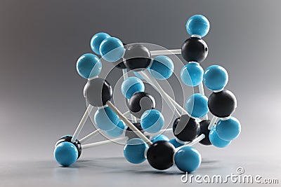 Molecular model structure, miniature on grey background, blue and black cells connected Stock Photo
