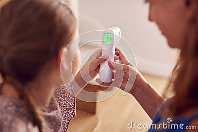 Close Up Of Mother Checking Daughters Temperature At Home Using Contactless Digital Thermometer Stock Photo