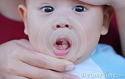 Close-up mother hands open baby mouth to examine first teeth. Infant primary tooth Stock Photo