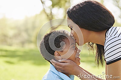 Close Up Of Mother Kissing Son In Park Stock Photo