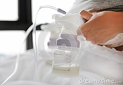 Close-up mother using automatic breast pump on the bed Stock Photo