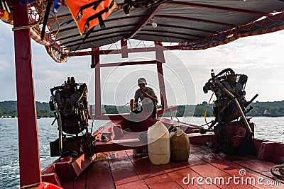 A close-up of a motor engine on a Cambodian longtail boat with captain Editorial Stock Photo