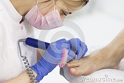 Close-up nail care by a pedicure specialist in a beauty salon. Pedicure transparent cuticle professional scissors for pedicure Stock Photo