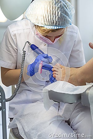 Close-up nail care by a pedicure specialist in a beauty salon. Pedicure transparent cuticle professional scissors for pedicure Stock Photo