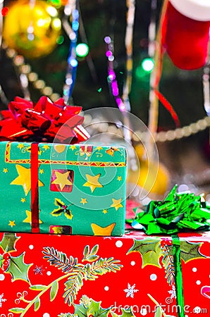 A close-up of a New Year`s gift in a gift box with a bow and a soft blurred background of a dressed up Christmas tree Stock Photo