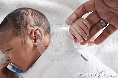 Close Up Of Newborn Baby In Cot Holding Parent`s Finger Stock Photo