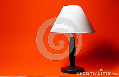 Close-up of night lamp with white shade and black tripod on background of lush lava color. Stock Photo