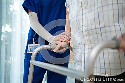 Close up of nurse help disable man walk with walker at nursing home. Caregiver therapist doctor support senior older handicapped Stock Photo