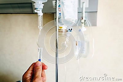 Close-up of a nurse`s hand adjusting the physiological serum dropper in a hospital Stock Photo