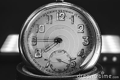 Close up of an An old clock face with numbers. Scratches on the glass. Silver chrome metal. Black background. Black and white Stock Photo