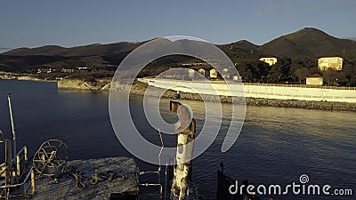 Close-up of old and destroyed ship trunk and gull sitting on a rusty pipe against the sunset sky. Shot. Marine Stock Photo